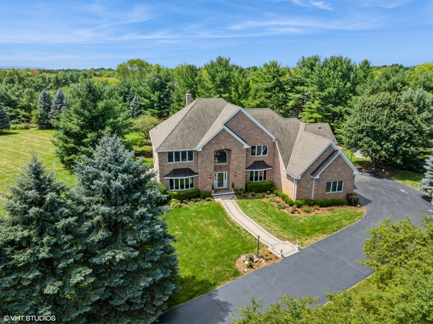 a view of a house with a big yard plants and large trees