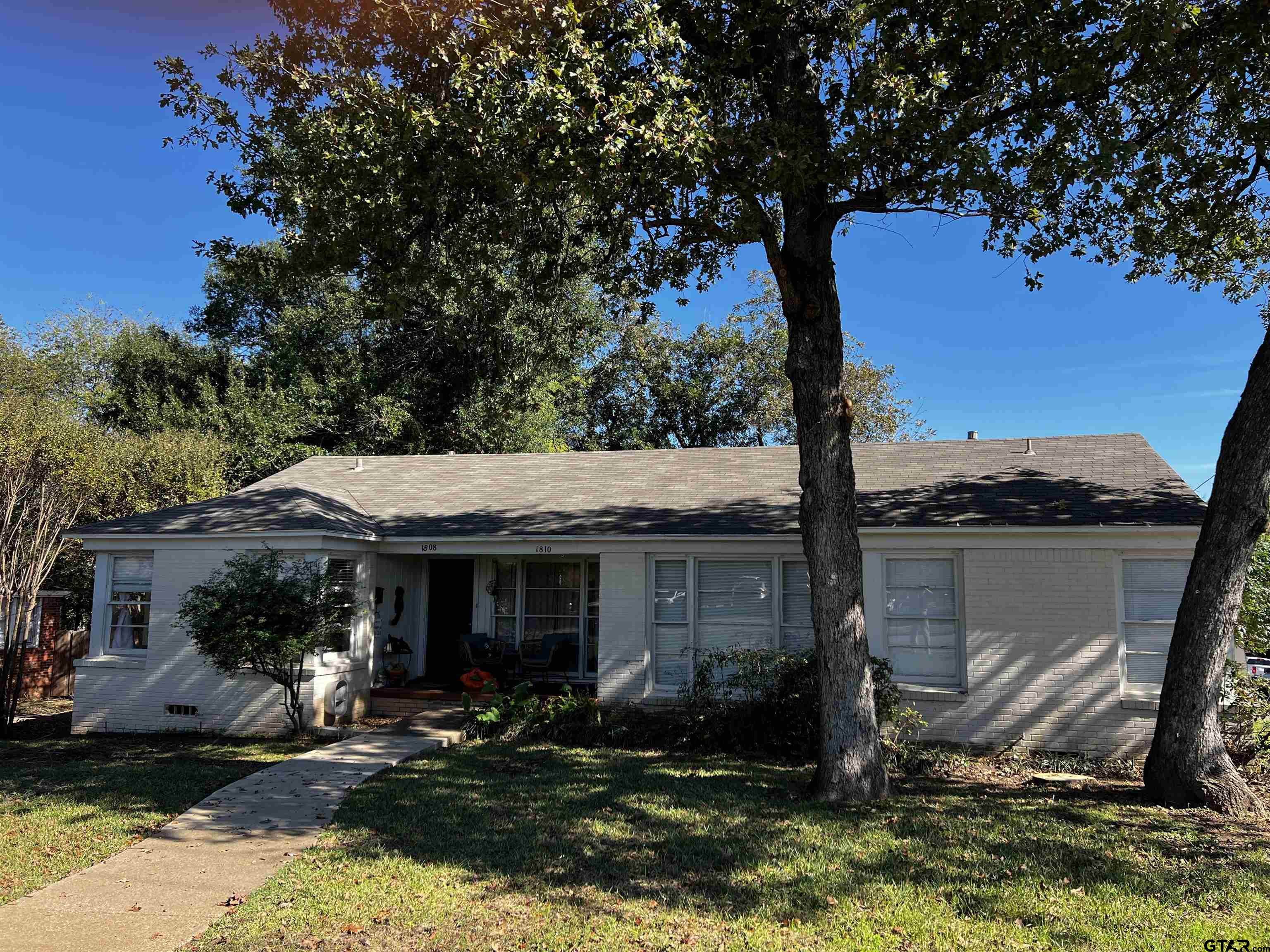 a front view of a house with a yard tree and outdoor seating