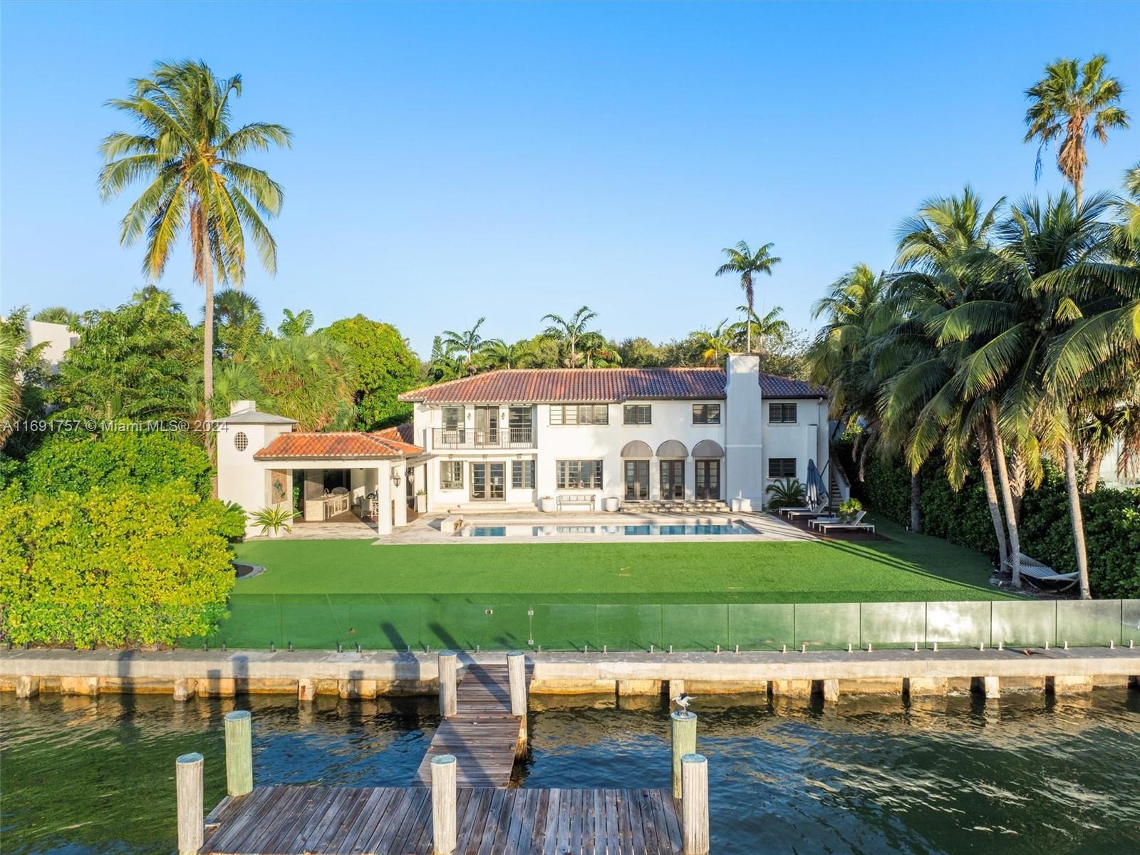 a view of a lake with a house and a yard with swimming pool