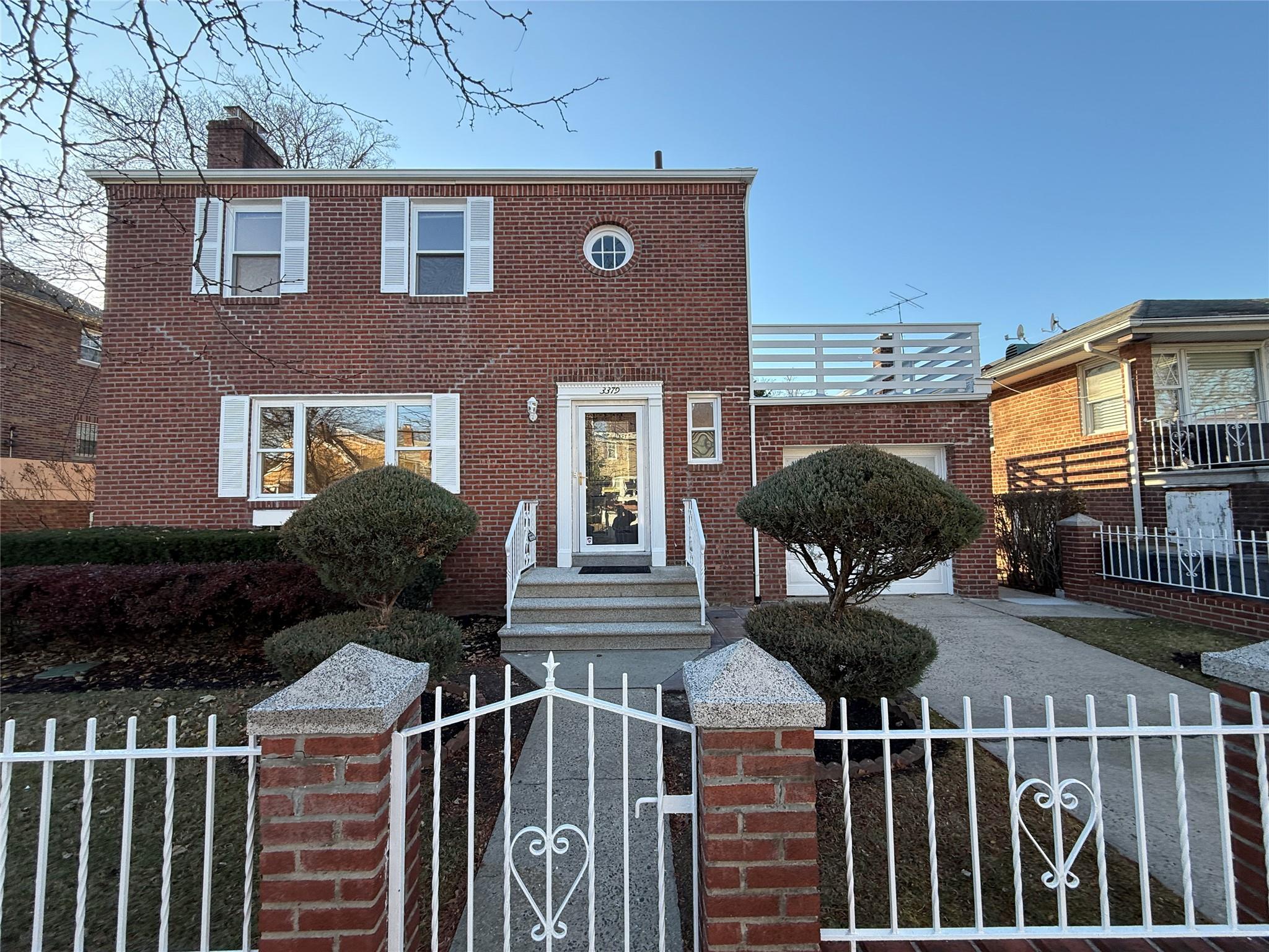 a view of a brick house with iron fence