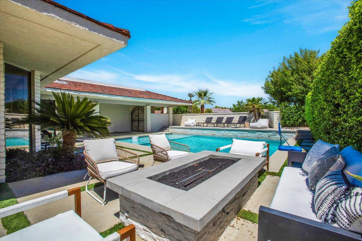 a view of a patio with couches table and chairs with potted plants and a palm tree