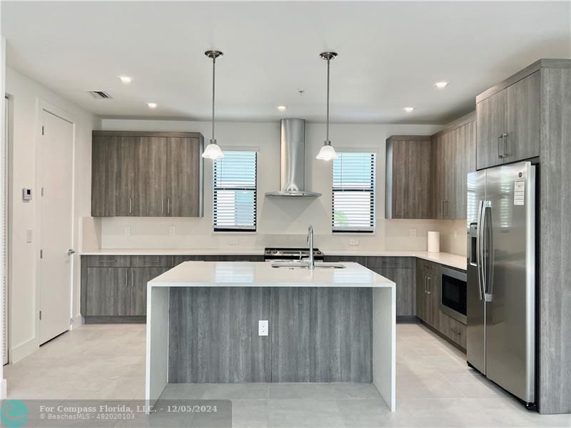 a kitchen with kitchen island a counter top space appliances and a sink