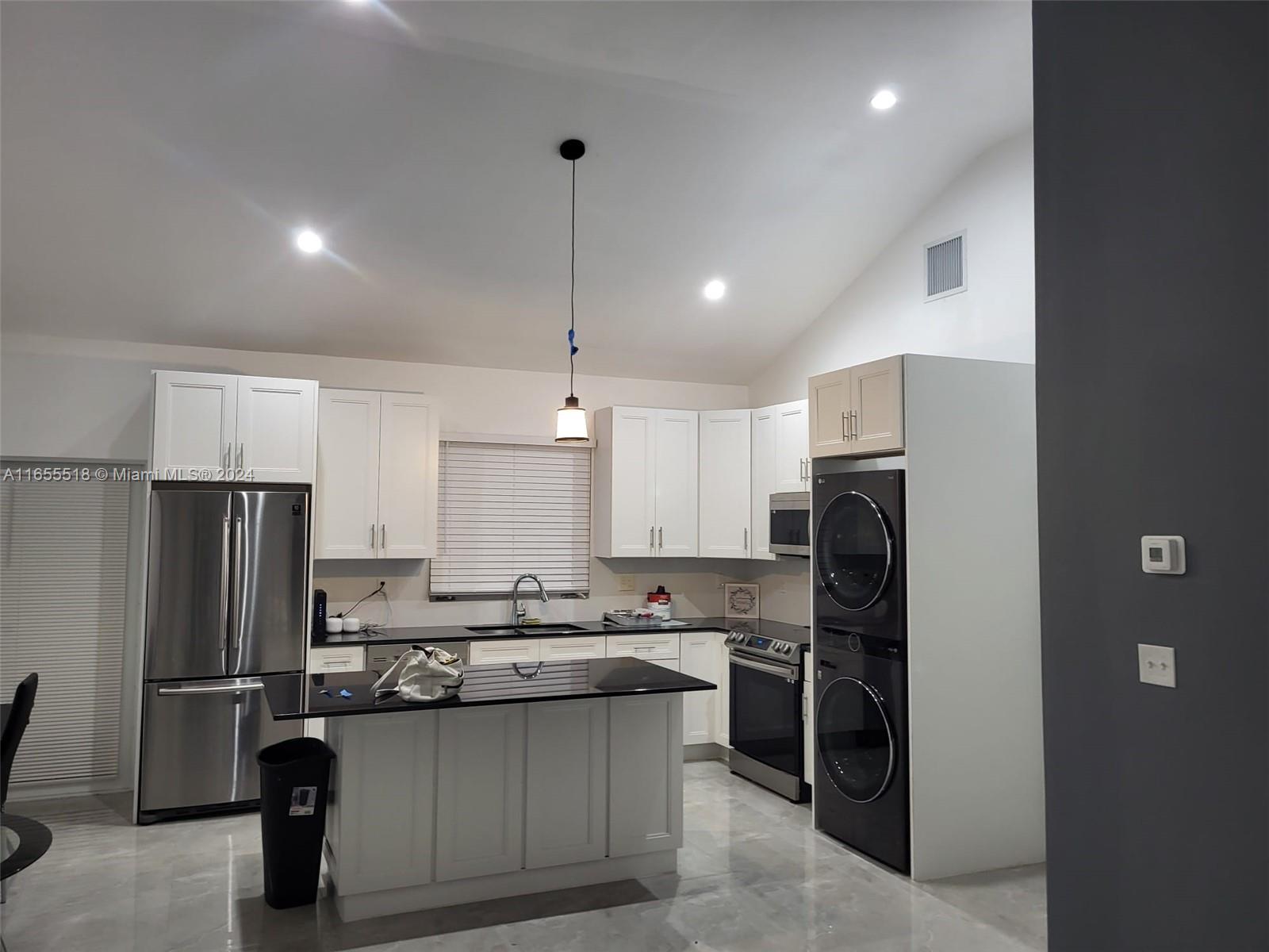 a kitchen with refrigerator a microwave a stove and white cabinets