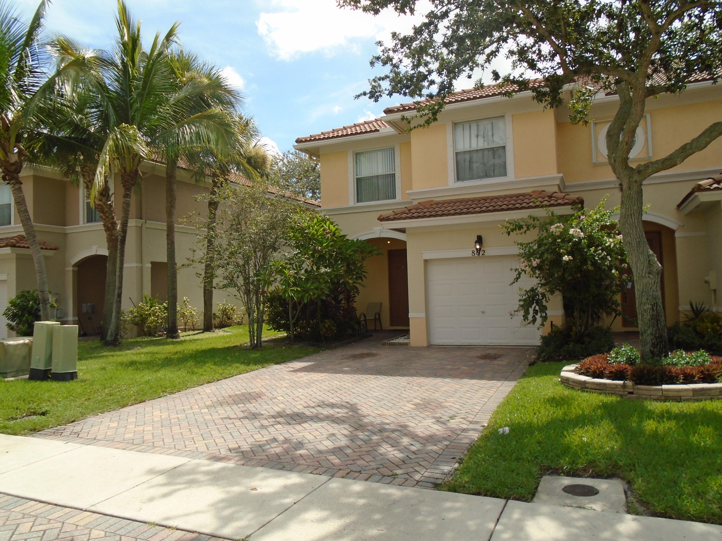 a front view of a house with a garden and trees