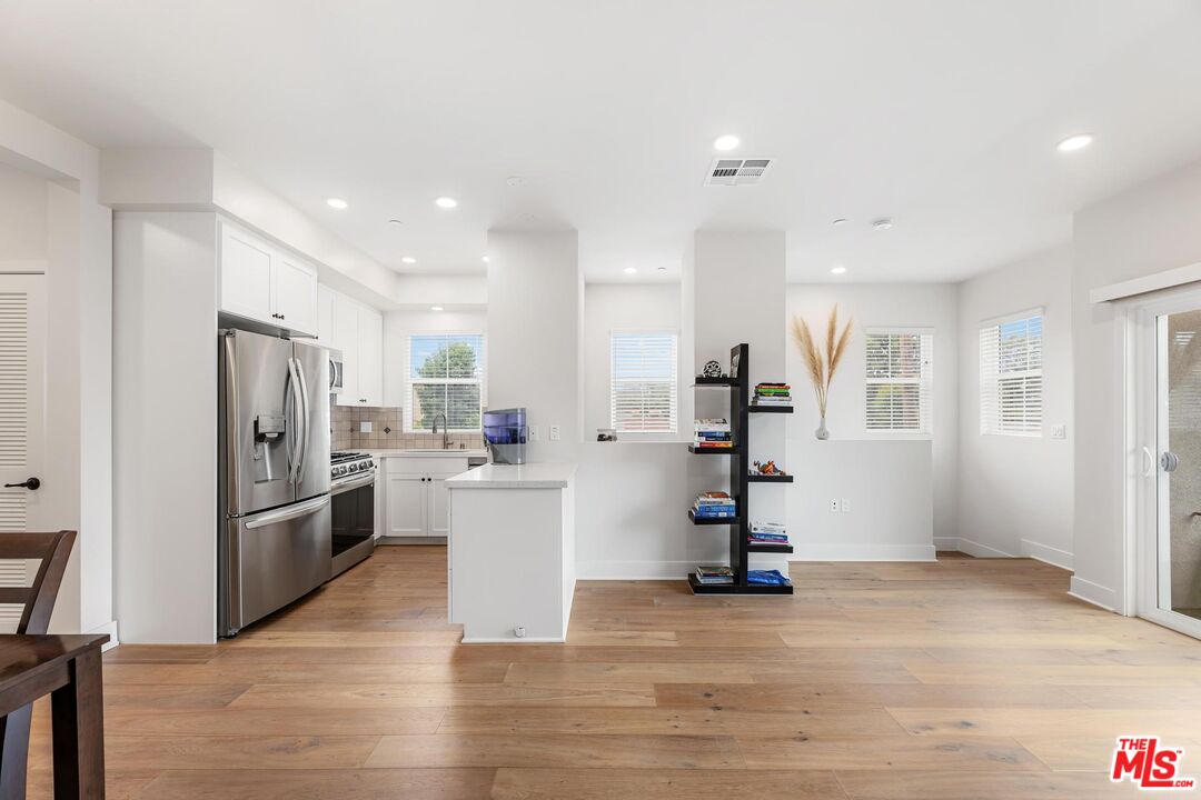 a view of a kitchen with refrigerator and wooden floor