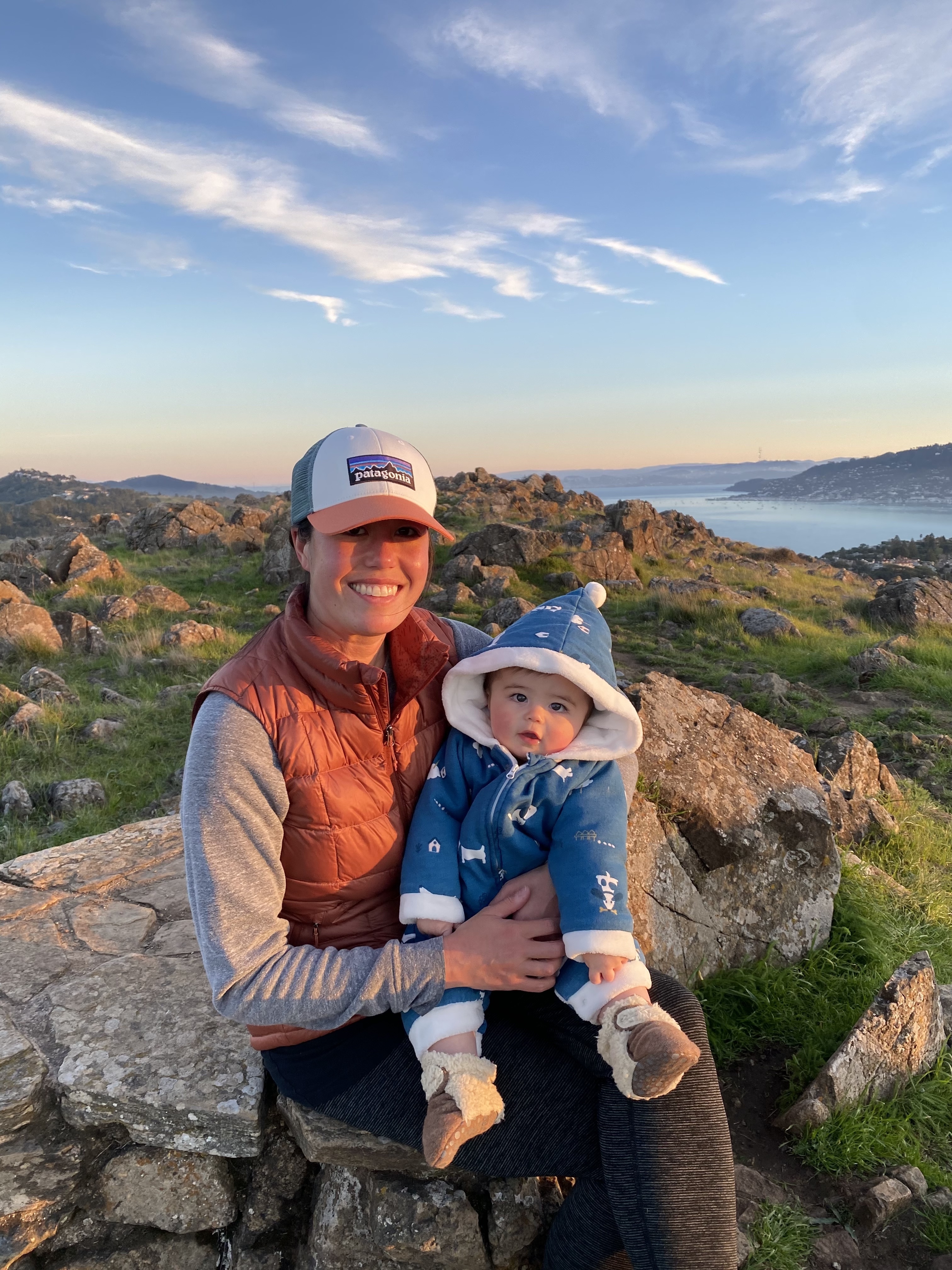 a man holding a small child next to a rock