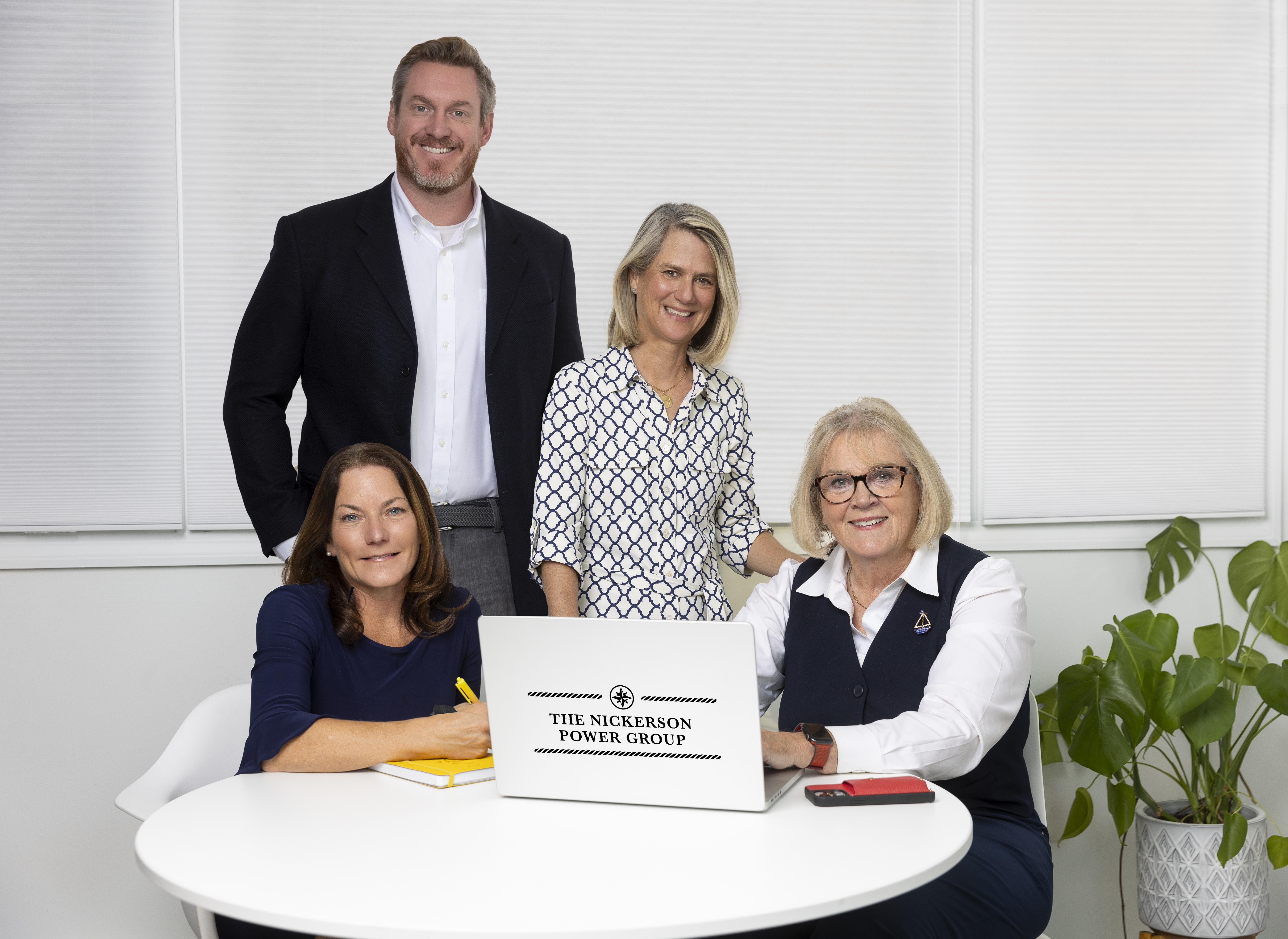 three women and one man sitting at a table with a laptop