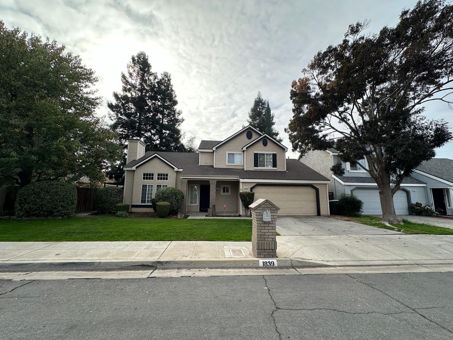 a front view of a house with a garden and trees