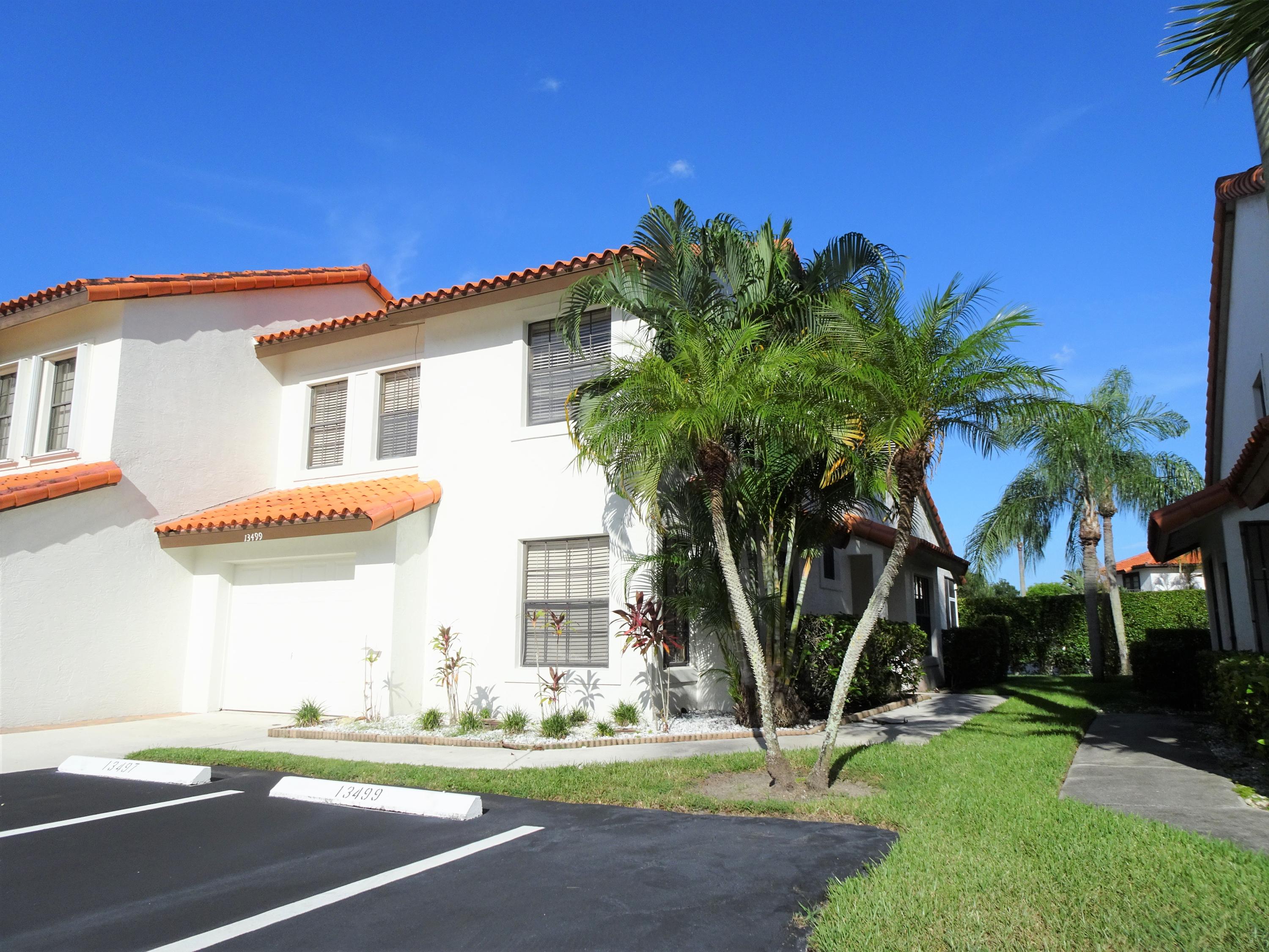 a view of a house with a yard and palm trees