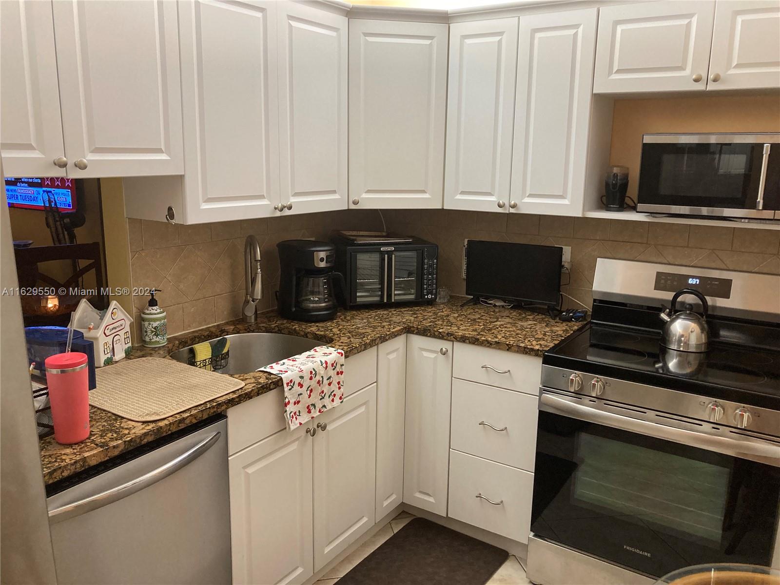 a kitchen with granite countertop white cabinets and white appliances