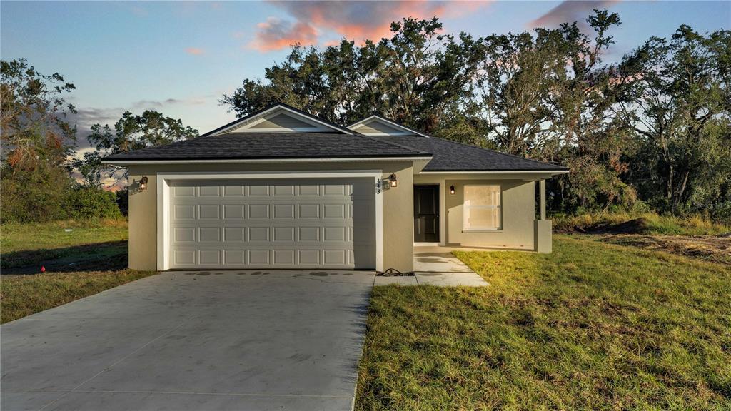 front view of house with a yard and trees all around