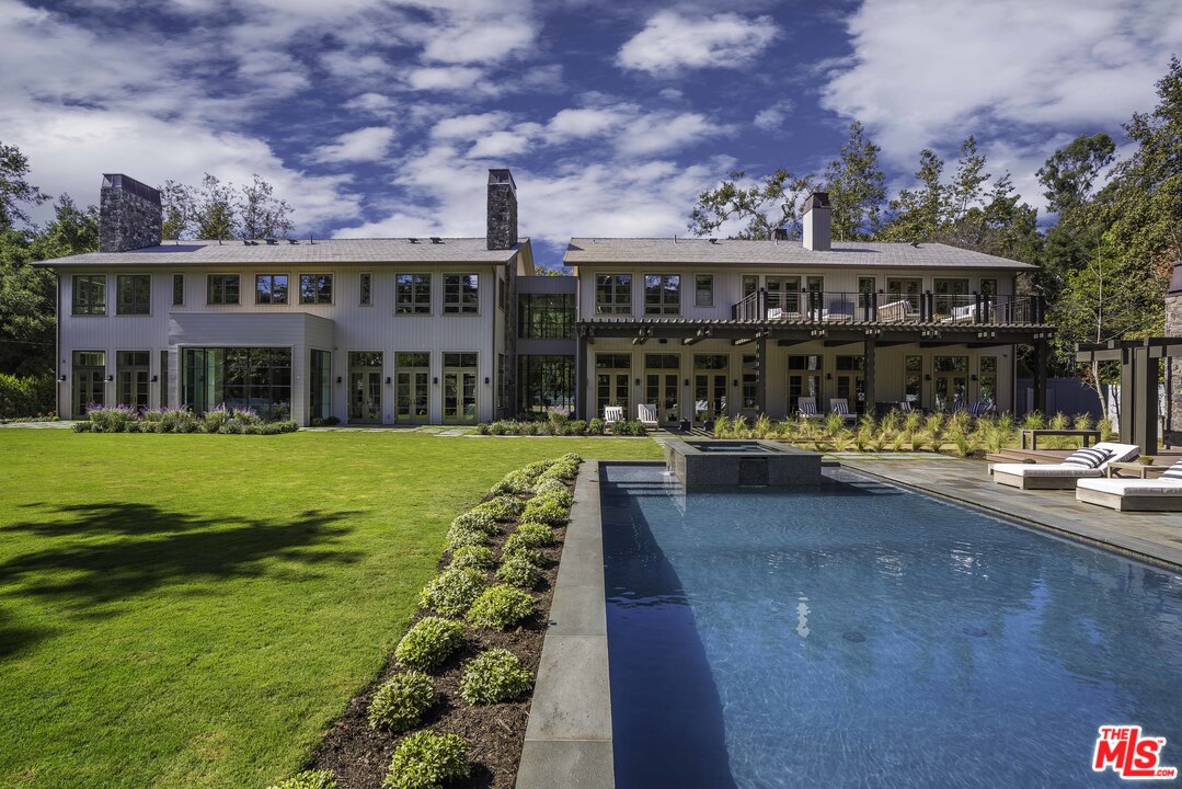 a view of swimming pool with lawn chairs and large trees