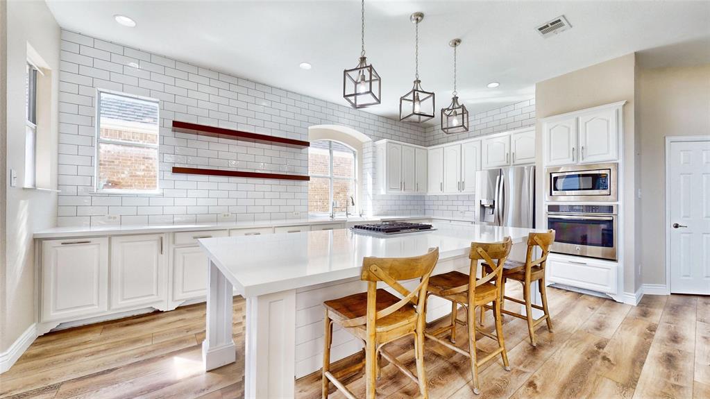 a kitchen with stainless steel appliances kitchen island granite countertop a dining table chairs sink and cabinets