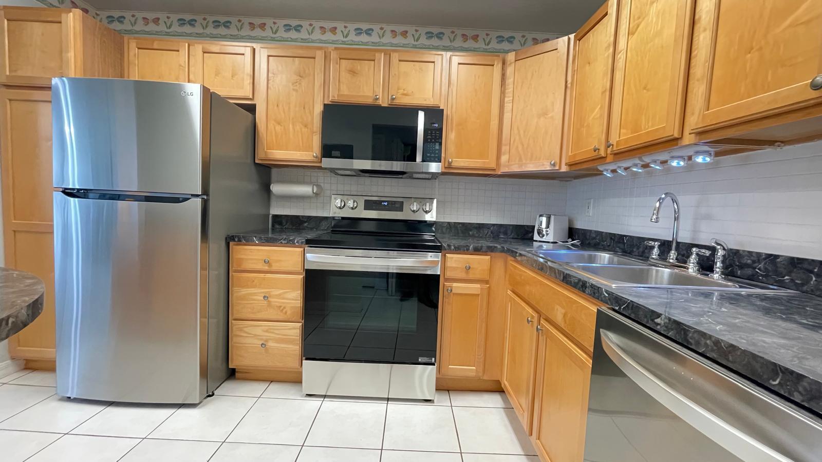 a kitchen with stainless steel appliances granite countertop a refrigerator sink and stove