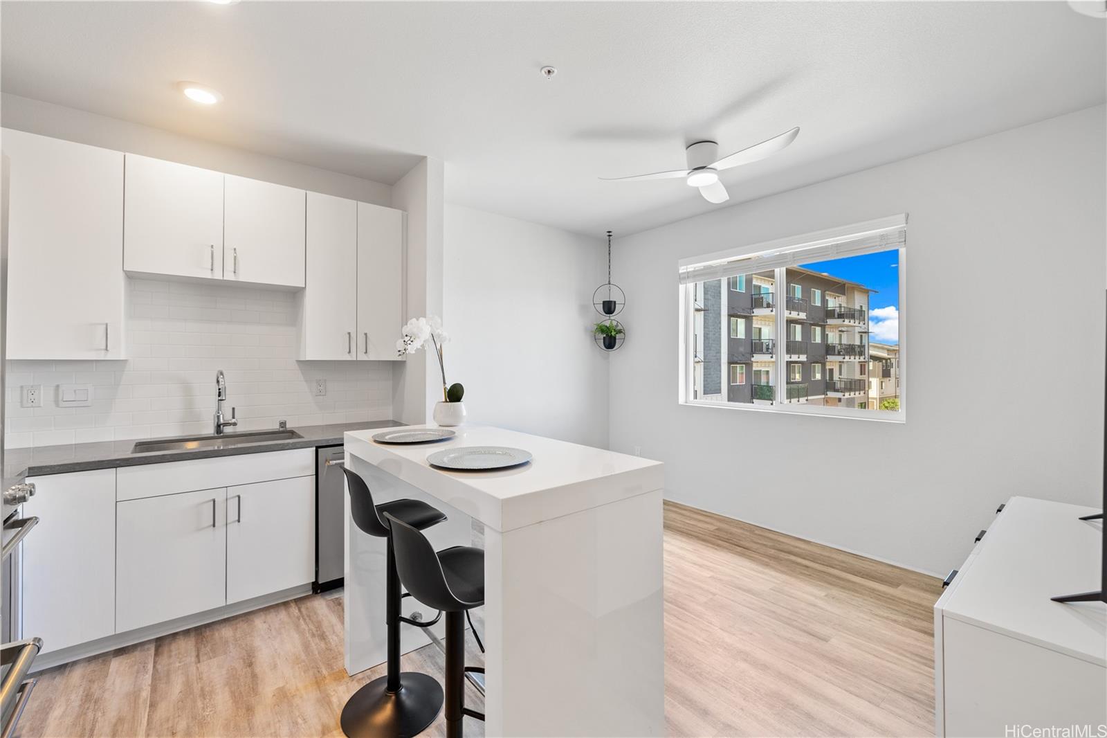 a kitchen with stainless steel appliances kitchen island a table chairs sink and cabinets