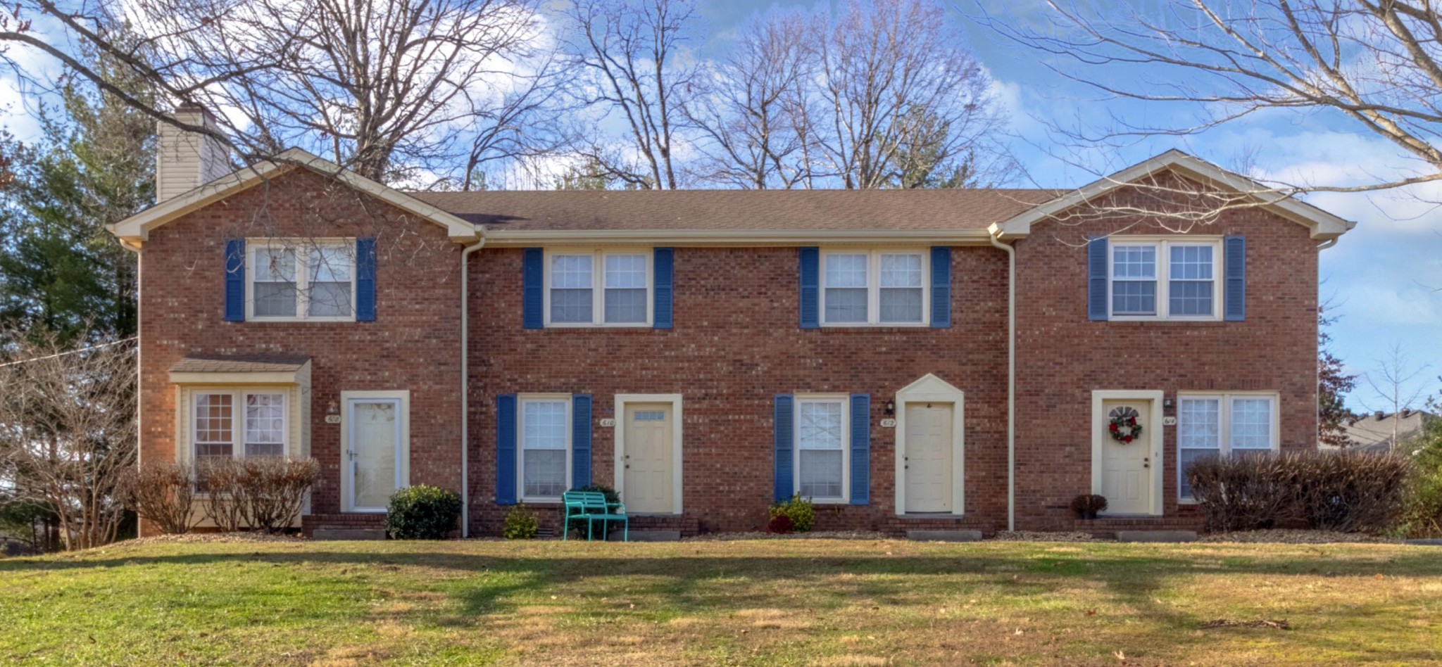 a front view of a house with a yard and large trees