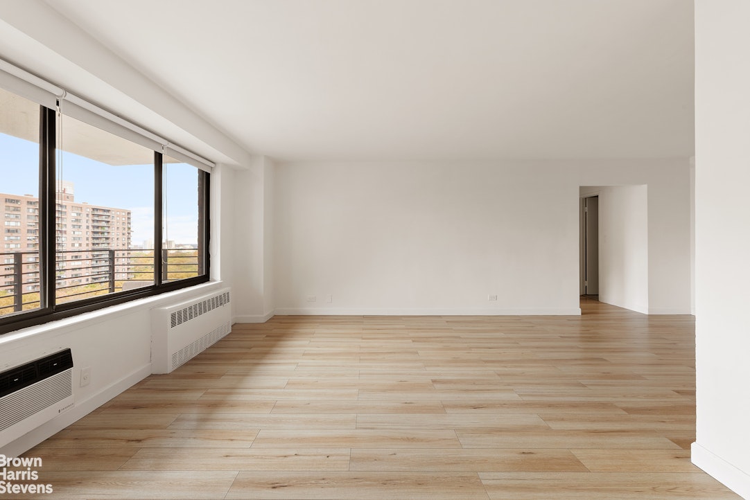 a view of an empty room with a window and wooden floor