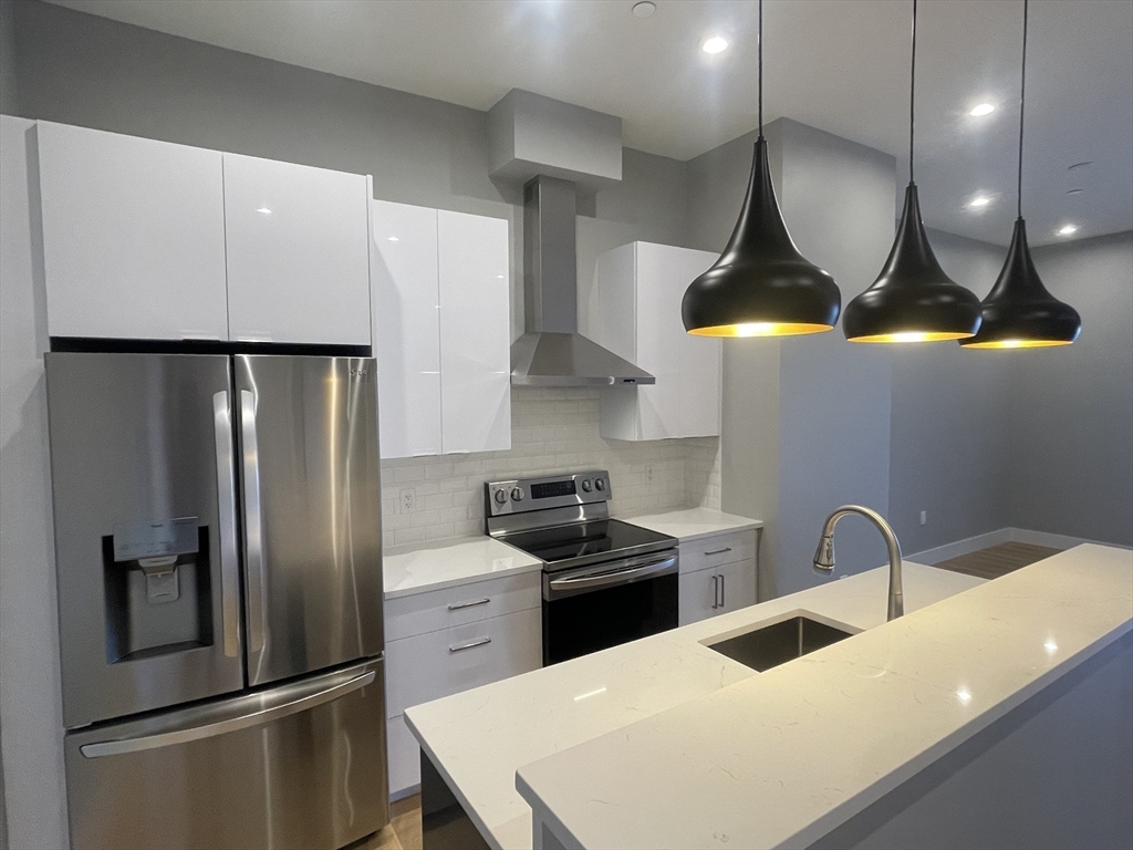 a kitchen with stainless steel appliances a sink a stove a refrigerator and cabinets