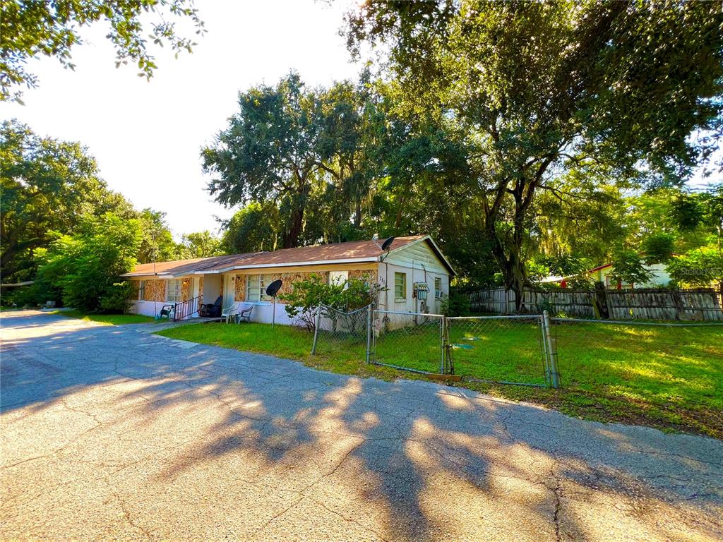 a view of a house next to a big yard and large trees