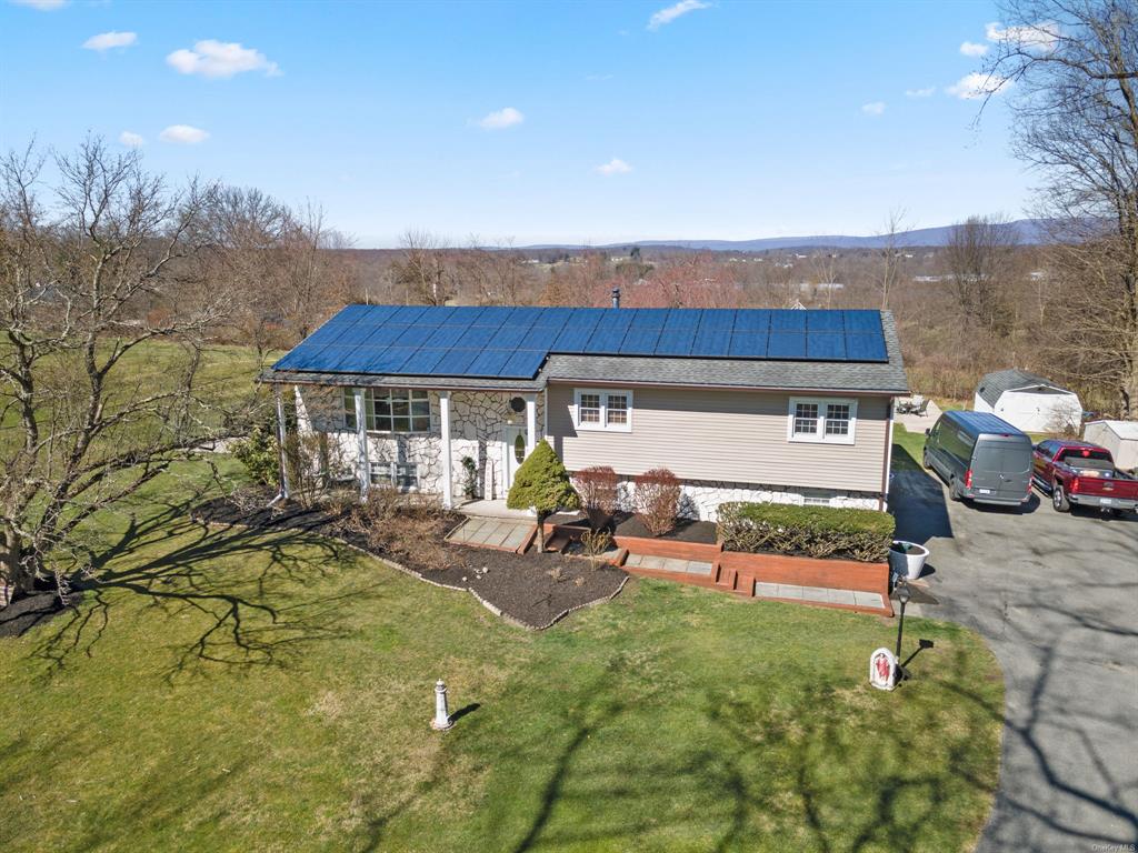 View of front facade with solar panels and a front lawn