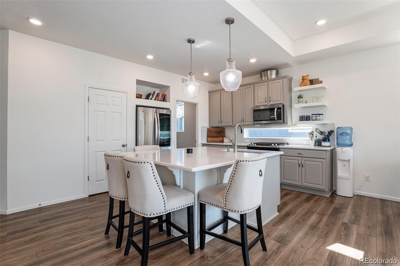 a kitchen with stainless steel appliances kitchen island granite countertop a table chairs and a refrigerator