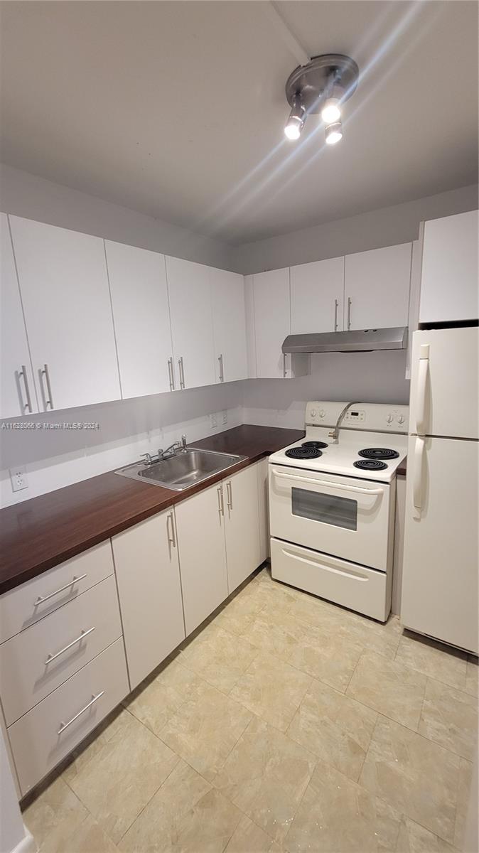 a kitchen with granite countertop white cabinets and white appliances