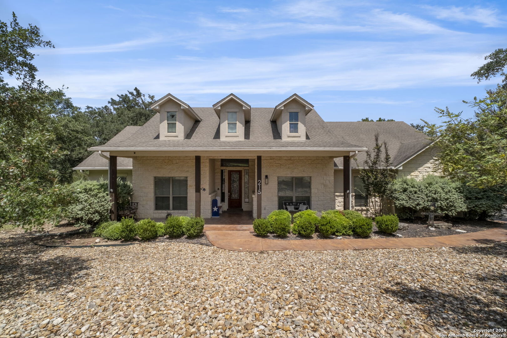 a front view of a house with garden and trees