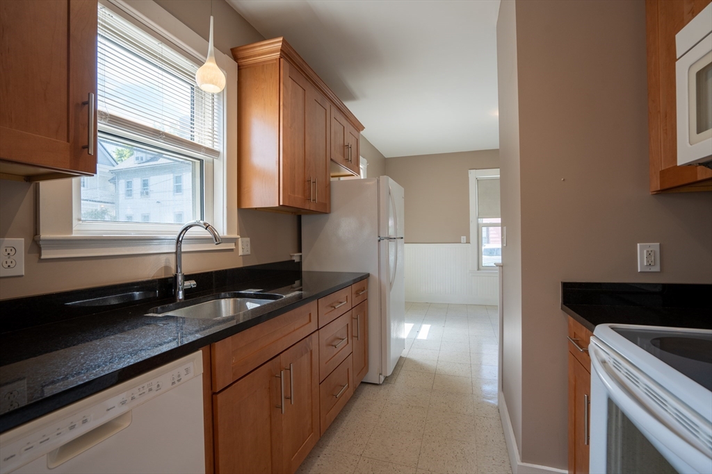 a kitchen with granite countertop a sink and a refrigerator