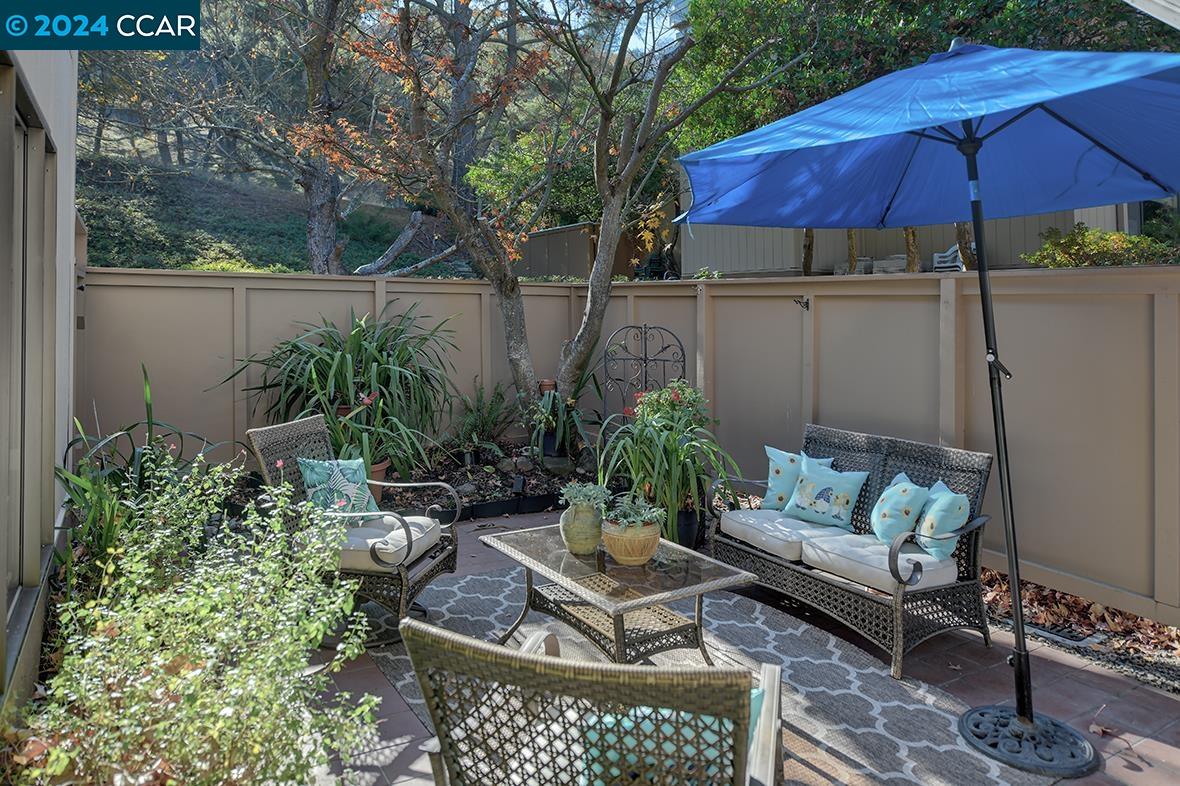 a patio with tables and chairs under an umbrella