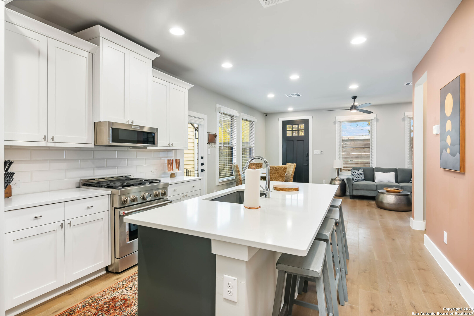 a large white kitchen with sink a stove and white cabinets
