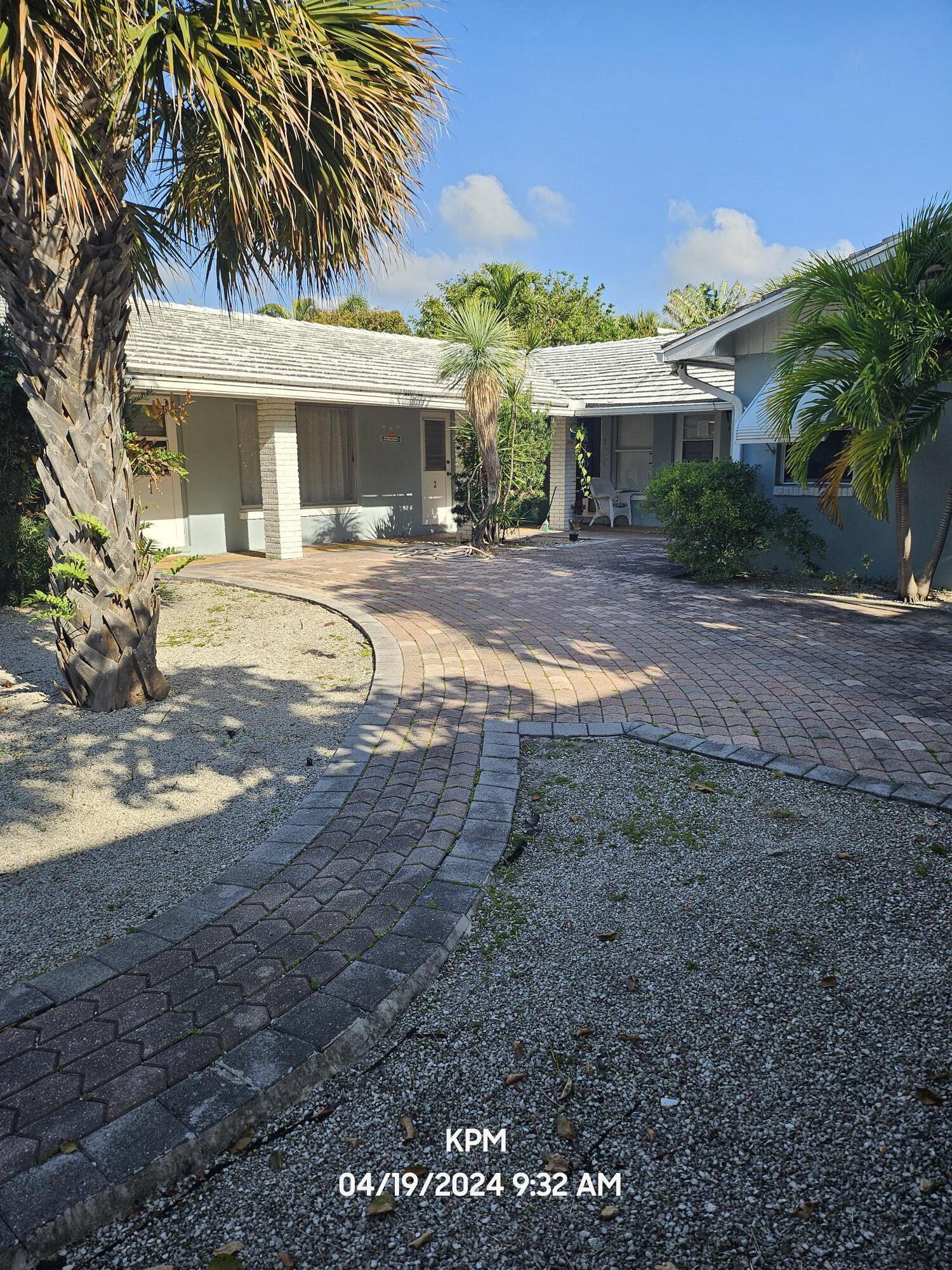 a view of a white house with a yard and palm trees