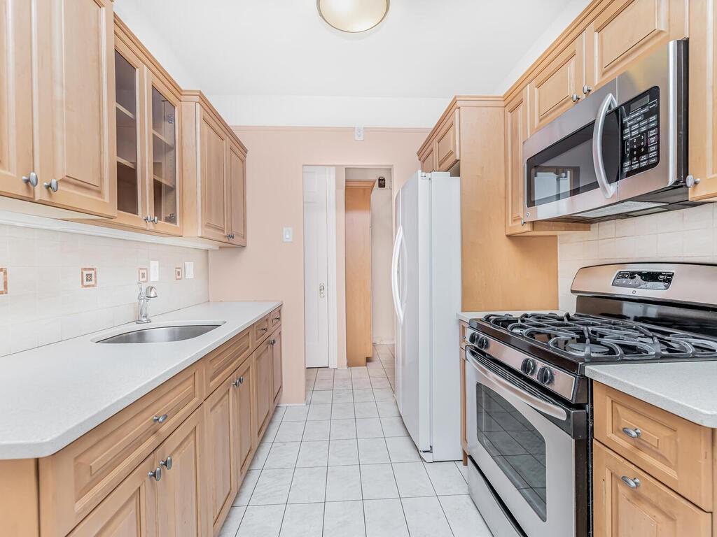 Kitchen featuring sink, light tile patterned floors, tasteful backsplash, and stainless steel appliances