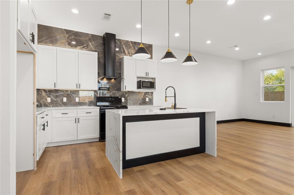 a kitchen with stainless steel appliances granite countertop a sink a stove and a wooden floors