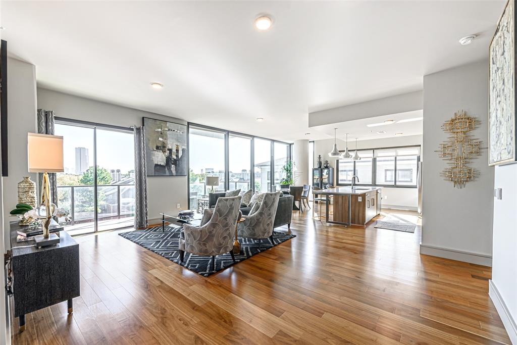 a living room with furniture large windows and wooden floor