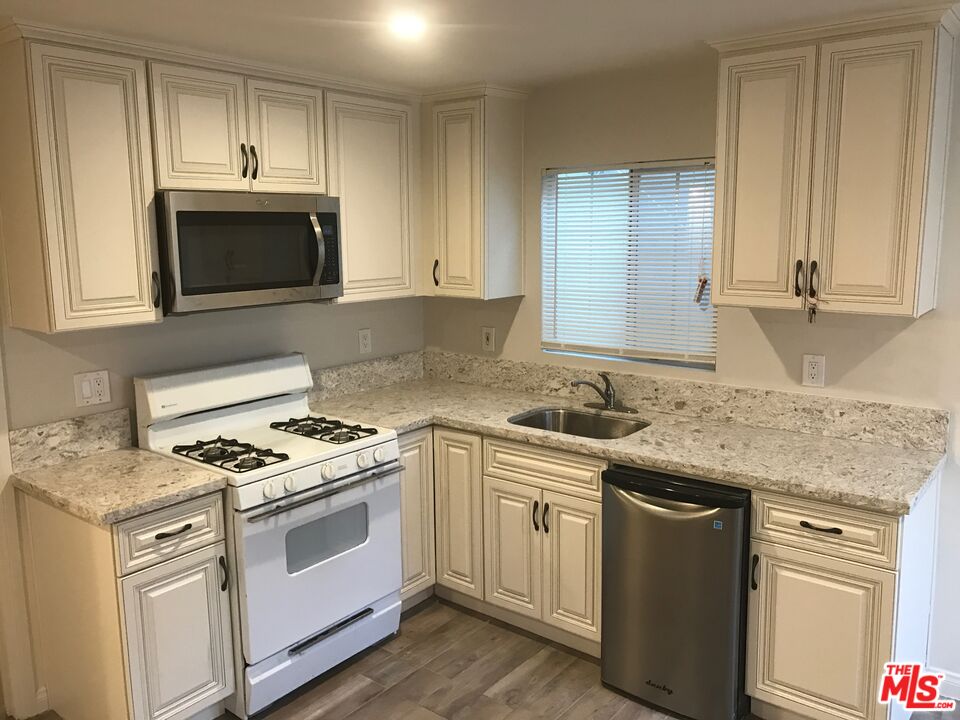 a kitchen with granite countertop a sink stove and microwave