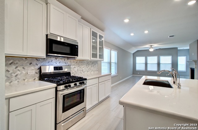 a kitchen with granite countertop a sink a stove and microwave