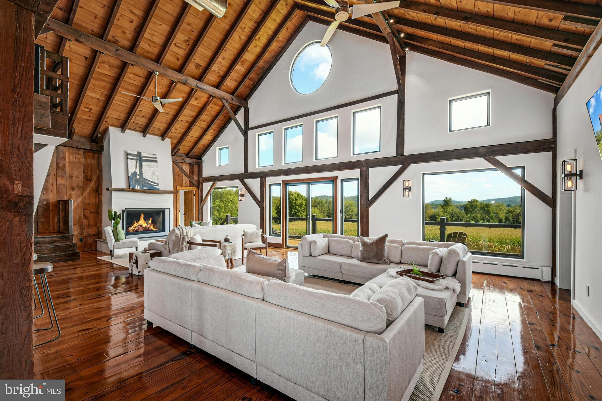 a living room with furniture large windows a fireplace and wooden floor