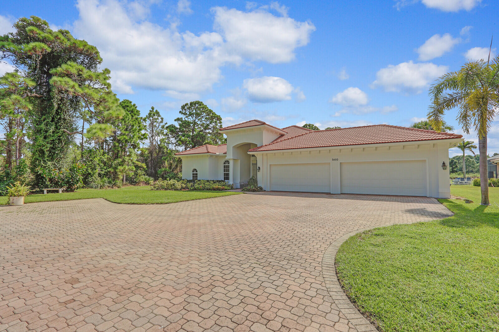 a view of a grey house with a big yard and large trees