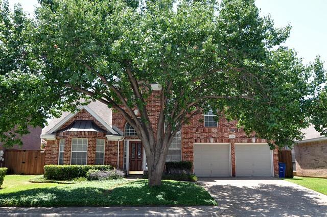 a front view of a house with a yard and large trees