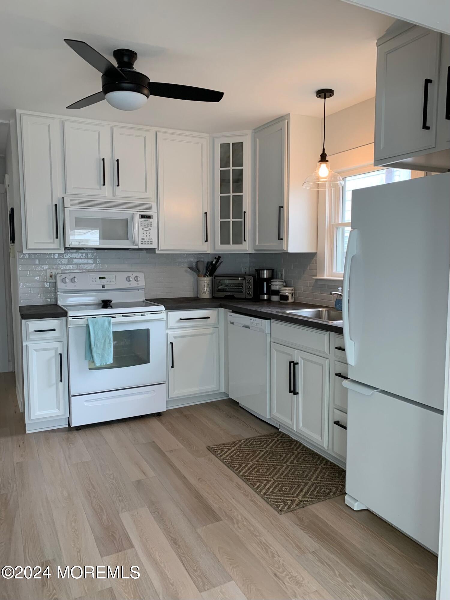 a kitchen with stainless steel appliances granite countertop a sink a stove a refrigerator and white cabinets