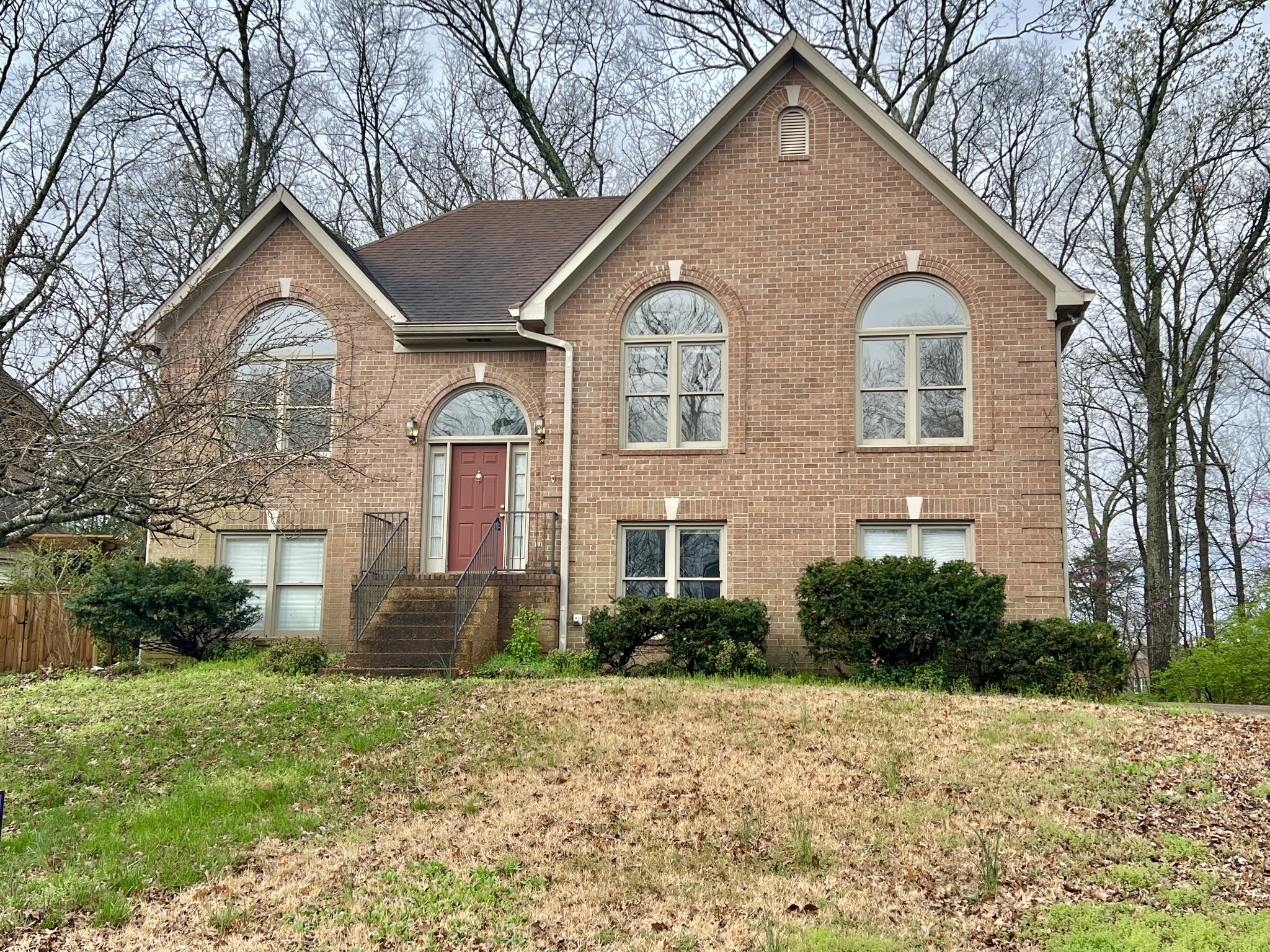 a view of a brick house with a yard and large trees