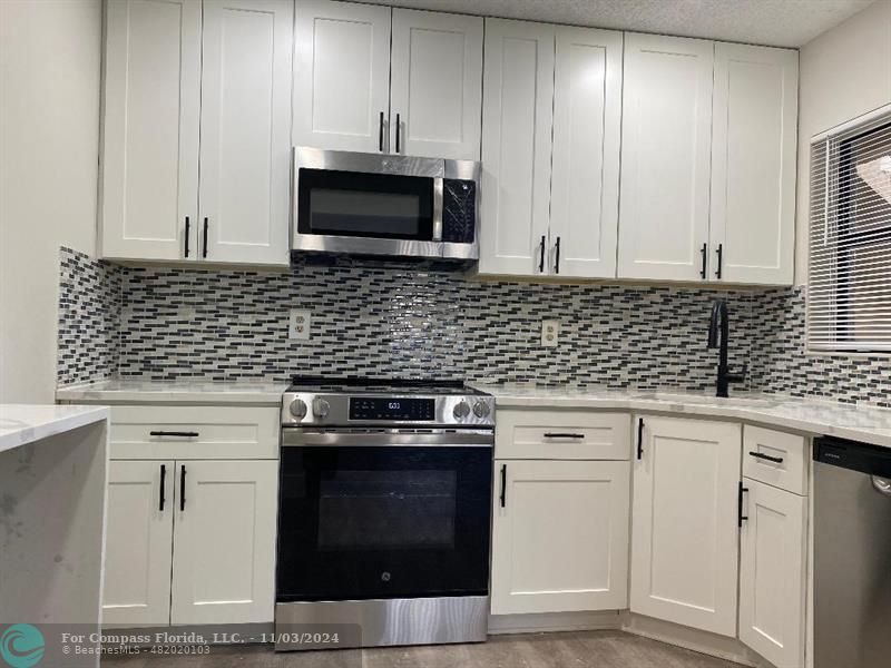 a kitchen with granite countertop white cabinets stainless steel appliances and sink