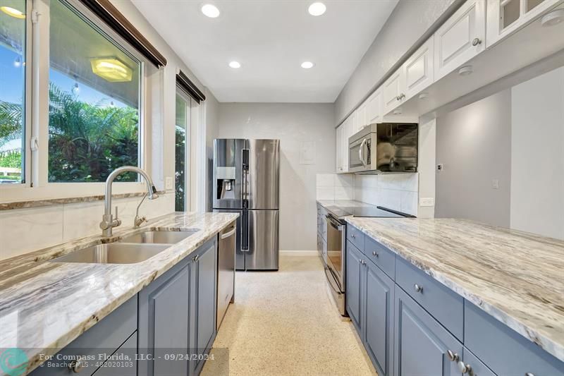 a kitchen with stainless steel appliances granite countertop a sink and a refrigerator