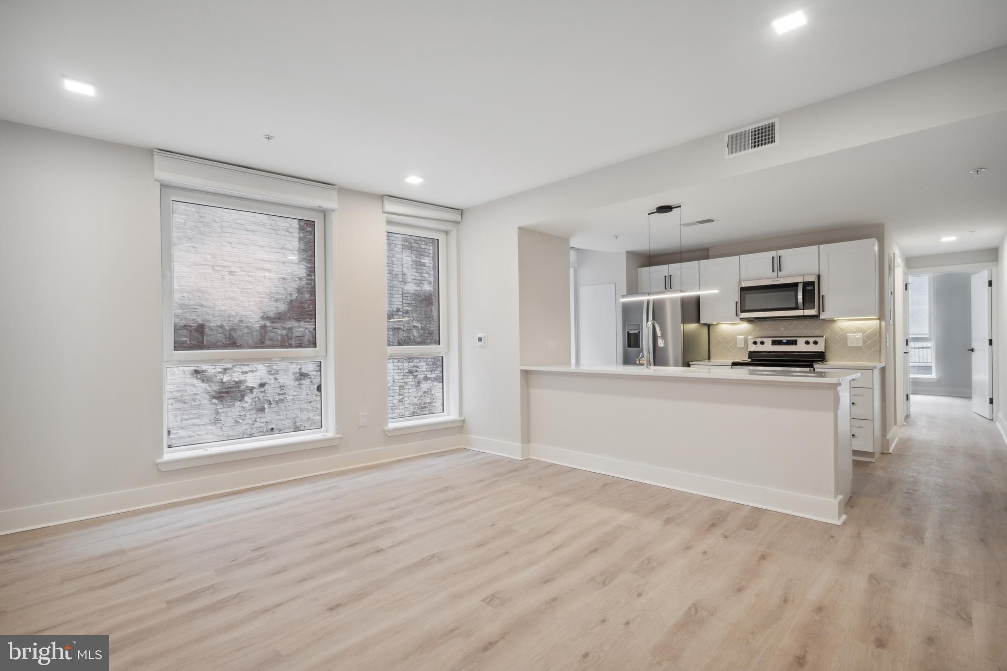 a view of kitchen with kitchen island wooden floor center island and stainless steel appliances