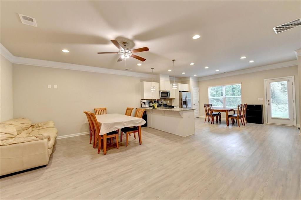 a living room with furniture and kitchen view with wooden floor