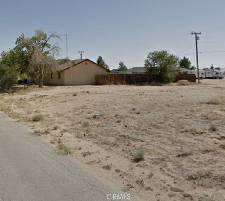 a view of a dry yard with wooden fence