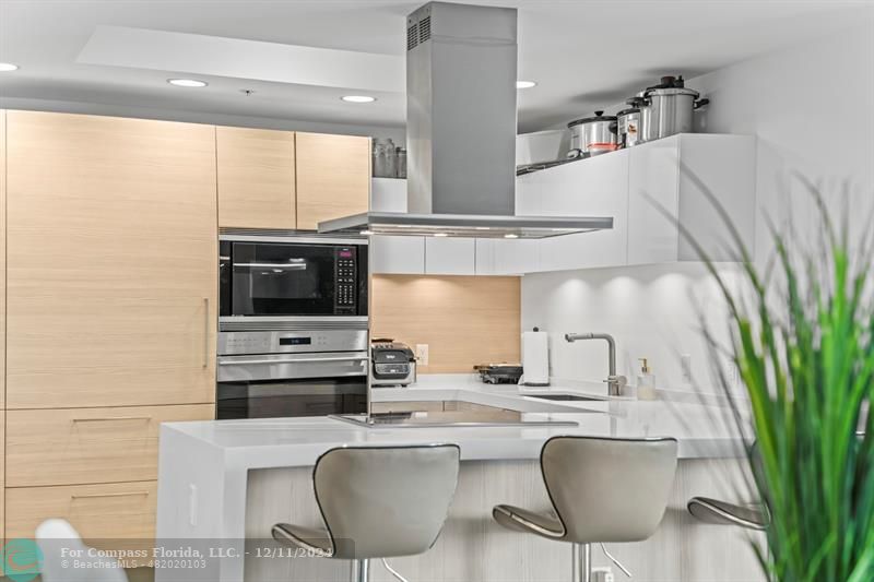 a kitchen with stainless steel appliances kitchen island granite countertop a sink and a refrigerator