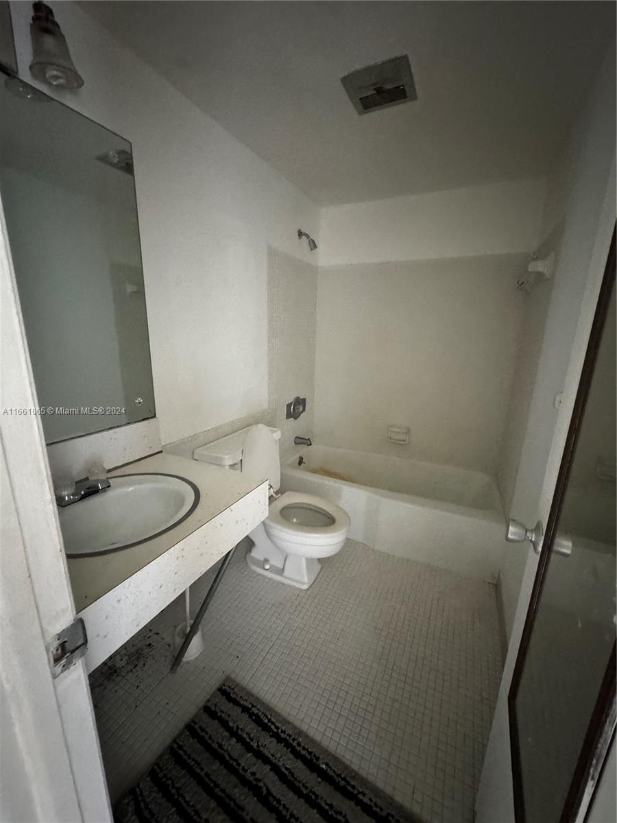 a bathroom with a granite countertop toilet sink and mirror