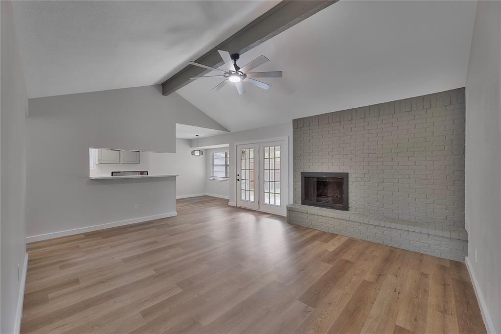 an empty room with wooden floor fireplace and windows