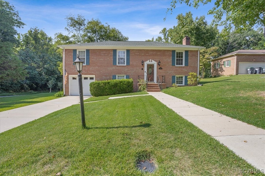 Raised ranch featuring a garage and a front lawn